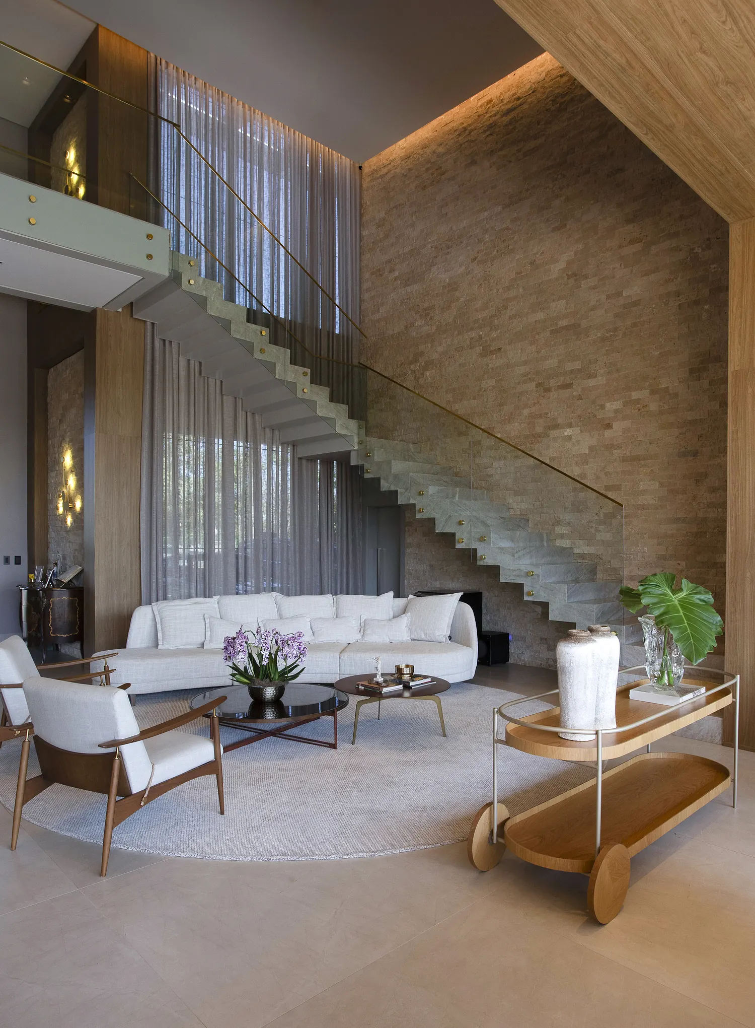 Living com parede de pedra e escada